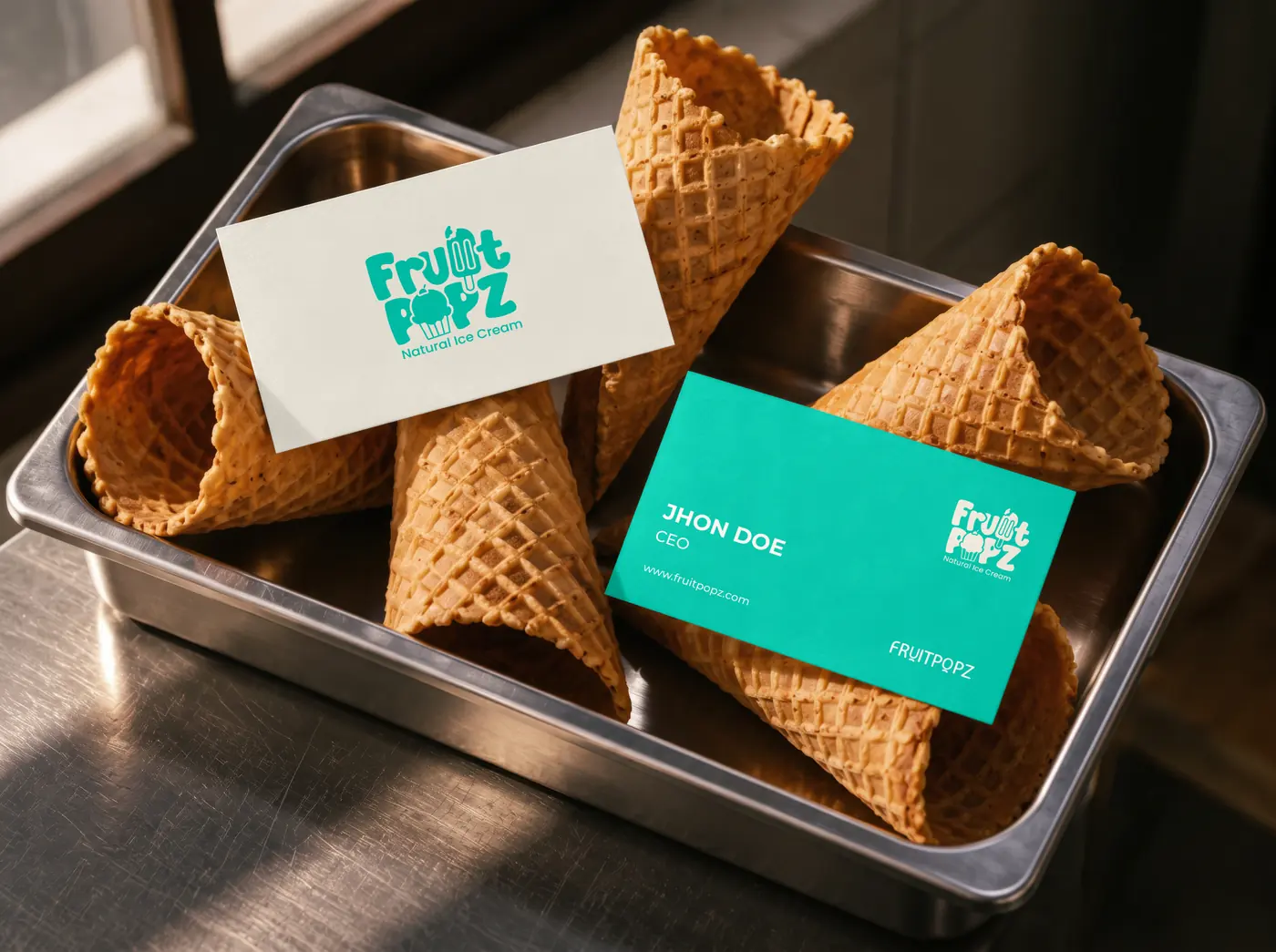 Fruitpopz business cards in aqua and old lace resting on waffle cones in a steel tray.